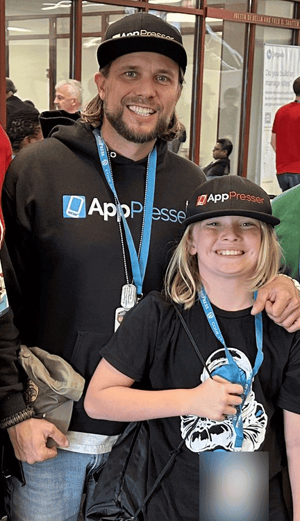 Brian Messenlehner and his young child in matching AppPresser hats and event lanyards