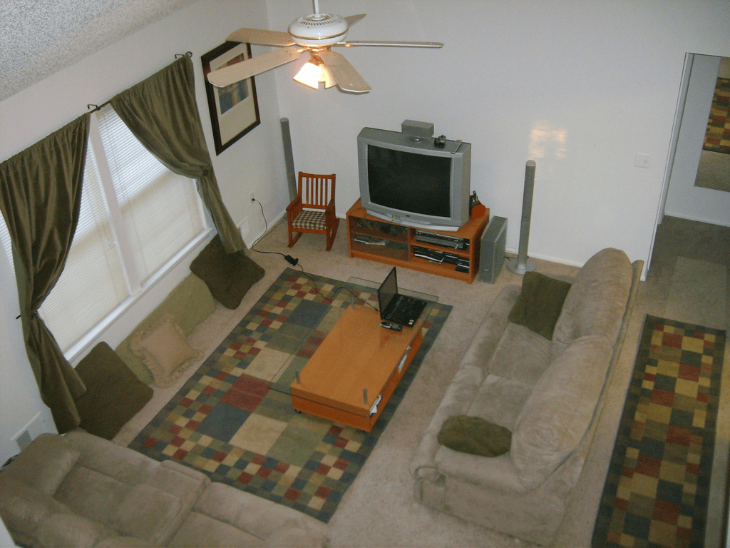 The living room of a condo seen from the loft, with a laptop on the coffee table