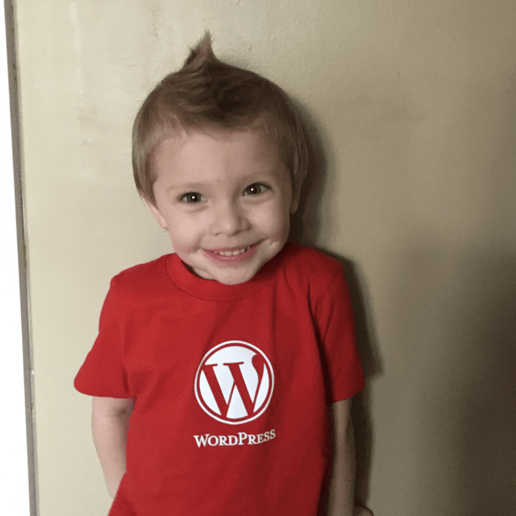 A smiling young child wearing a red WordPress logo T-shirt