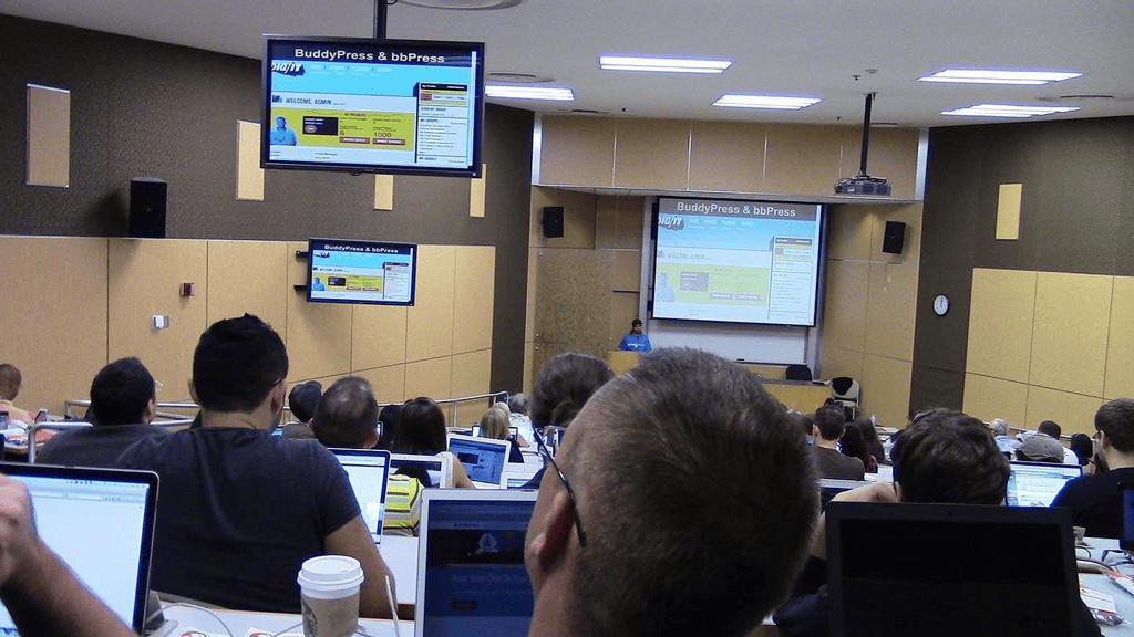 Brian Messenlehner presenting BuddyPress and bbPress to a lecture hall full of attendees with laptops