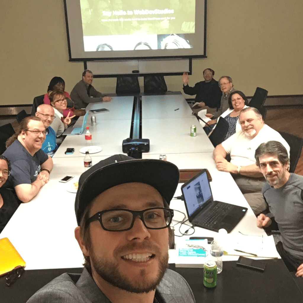 Brian Messenlehner taking a group selfie at a conference table with a WebDevStudios slide on the screen behind the group