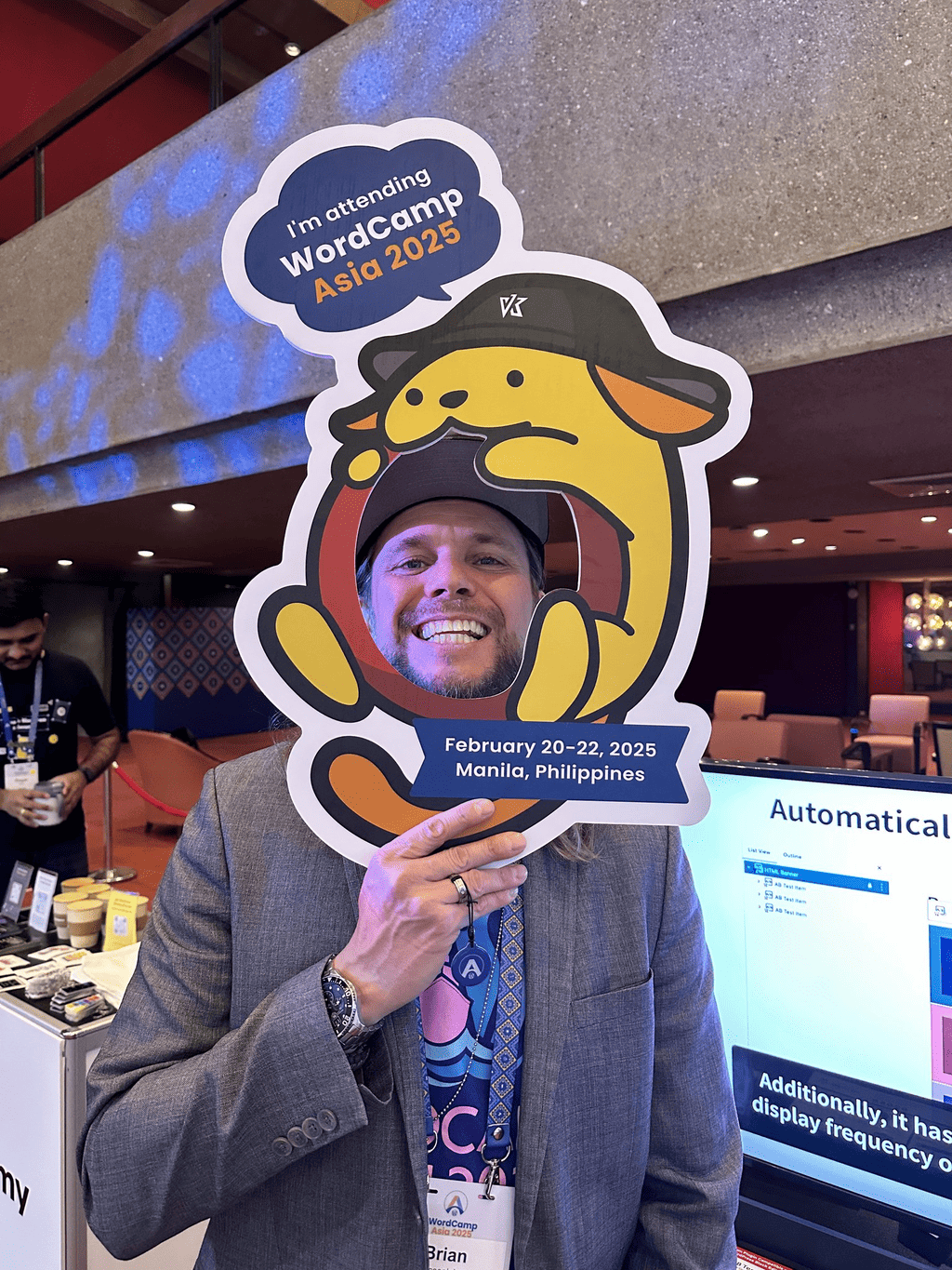 Brian Messenlehner smiling through a Wapuu photo board at WordCamp Asia 2025 in Manila