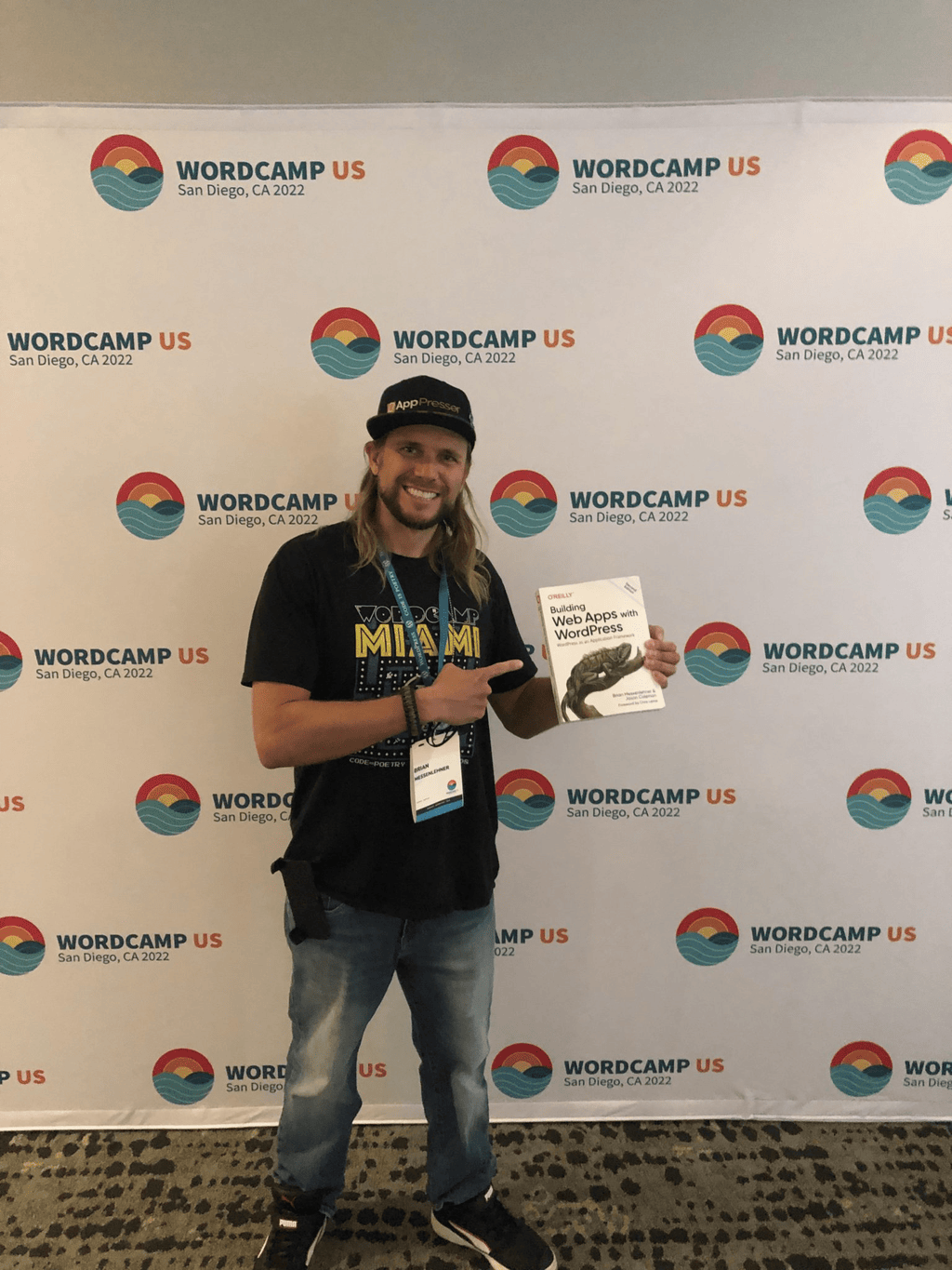 Brian Messenlehner holding his O'Reilly book Building Web Apps with WordPress at WordCamp US 2022 in San Diego