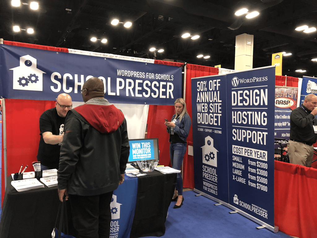 The SchoolPresser WordPress for Schools booth with banners for WordPress design hosting and support and yearly pricing by district size