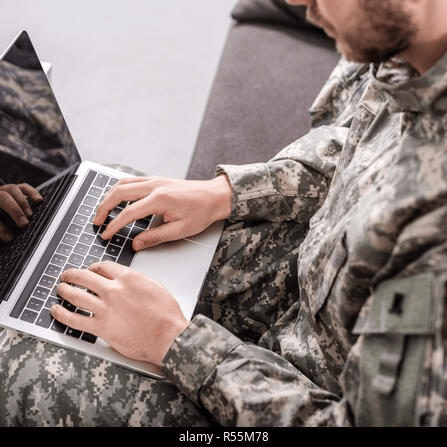 Service member in camouflage typing on a laptop
