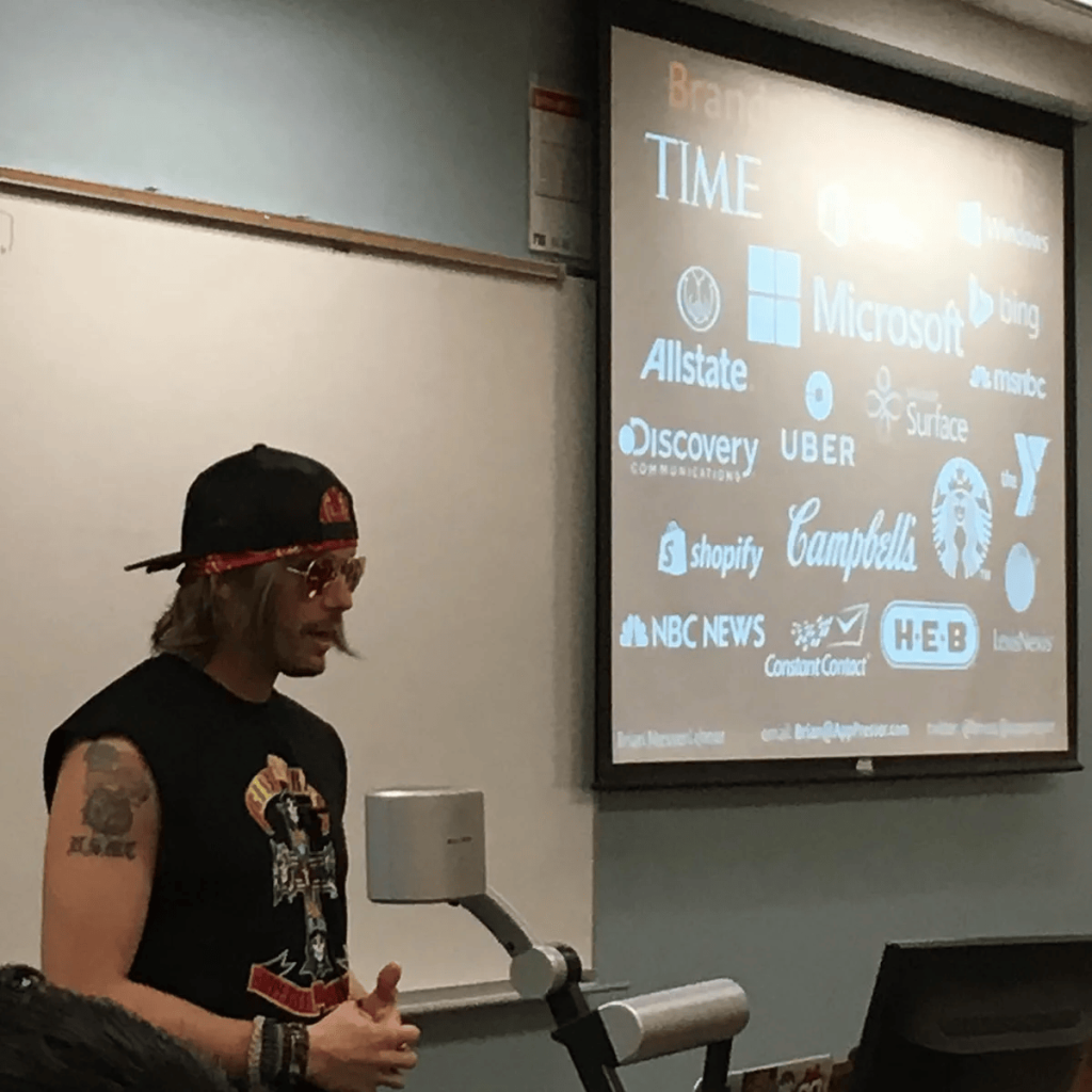 Brian dressed as Axl Rose in front of a slide of client brands