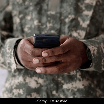 Service member in camouflage holding a smartphone